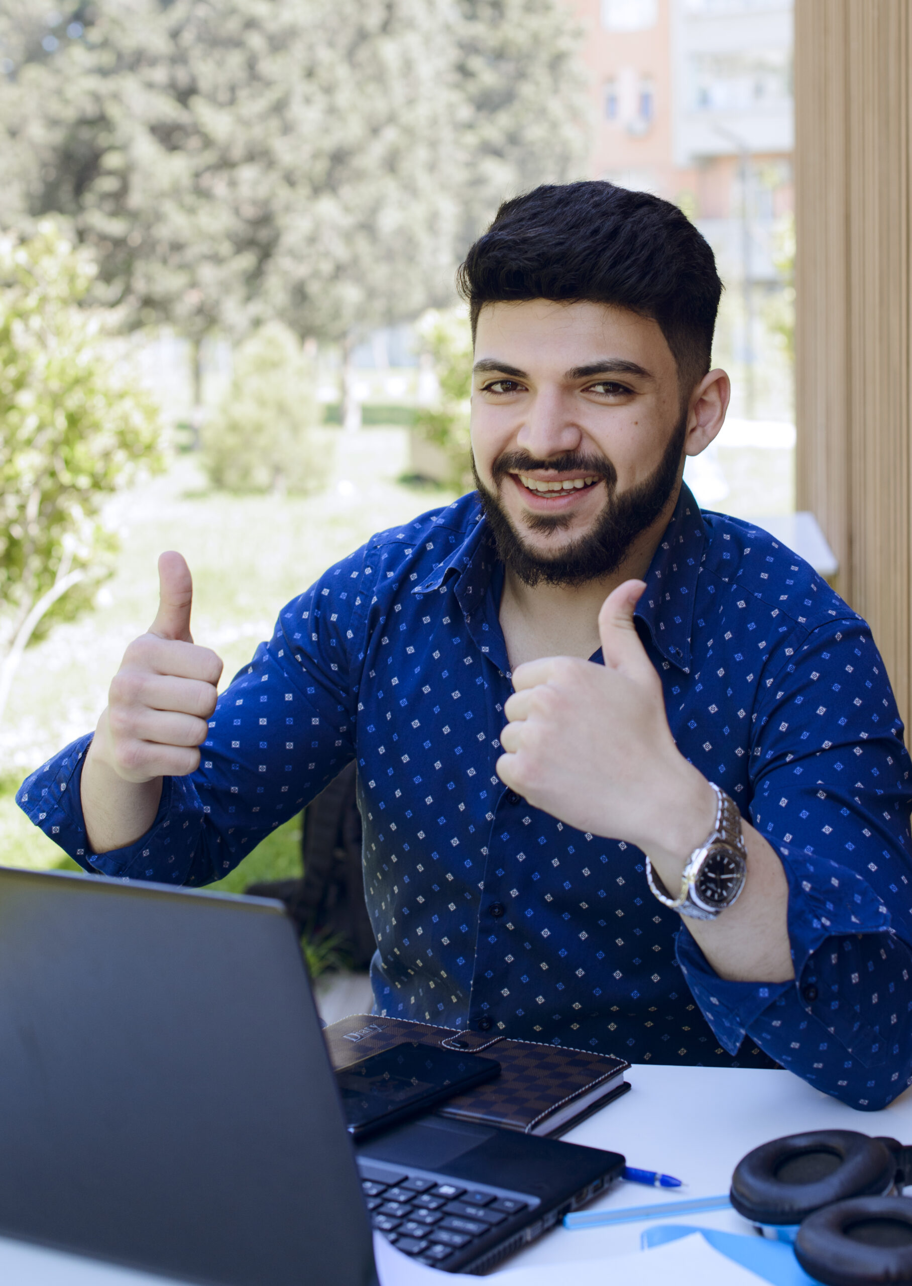 happy businessman holding thumbs up while looking camera while working scaled